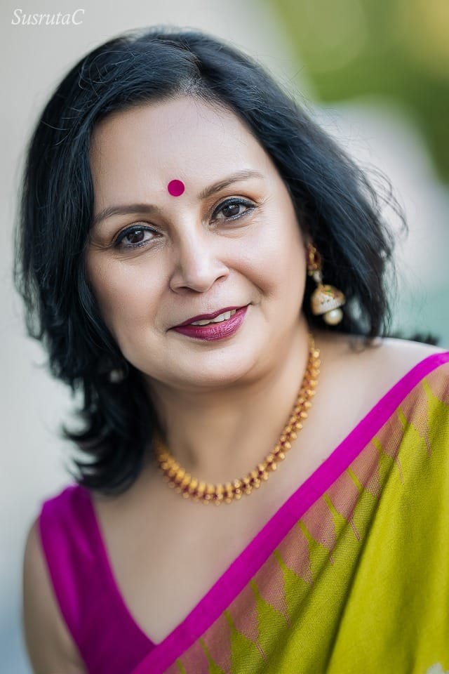 Outdoor head an shoulder portrait of a woman in a green sari with pink border and pink blouse